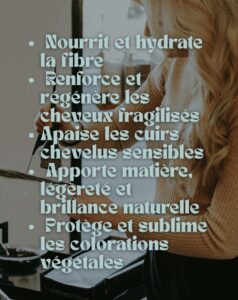 Image d'une femme aux longs cheveux blonds ondulés, vue de dos, tenant une mèche de cheveux avec une main. Le côté gauche de l'image est dominé par un texte en surimpression bleu clair listant les bienfaits des soins : 'Nourrit et hydrate la fibre, Renforce et régénère les cheveux fragilisés, Apaise les cuirs chevelus sensibles, Apporte matière, légèreté et brillance naturelle, Protège et sublime les colorations végétales'. L'ambiance est lumineuse et naturelle, suggérant un soin capillaire doux et efficace.